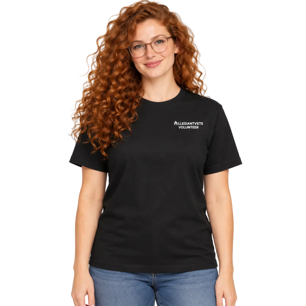 A woman with curly red hair and glasses wearing a black short-sleeve t-shirt with white text reading 'ALLEGIANTVETS VOLUNTEERS' on the left chest, paired with blue jeans, against a plain white background.