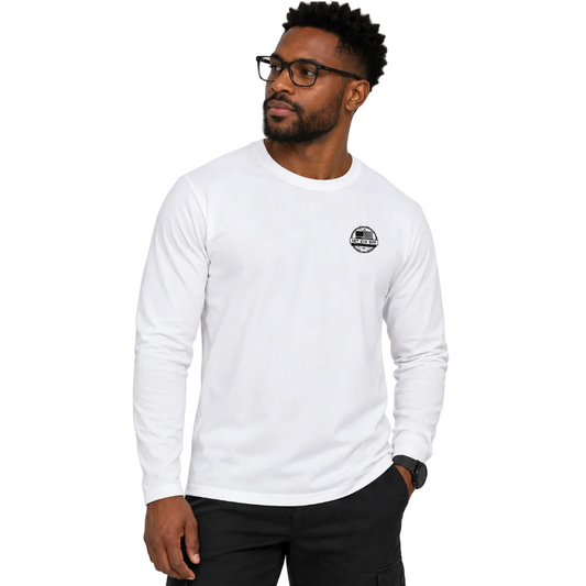 A man wearing a white long-sleeve crewneck t-shirt with a small black circular graphic on the left chest, paired with black cargo pants.