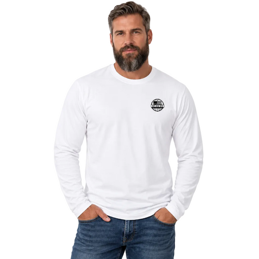 A man with a beard wearing a white long-sleeve crewneck shirt with a small black circular chest logo, paired with blue jeans, against a light gray studio background.