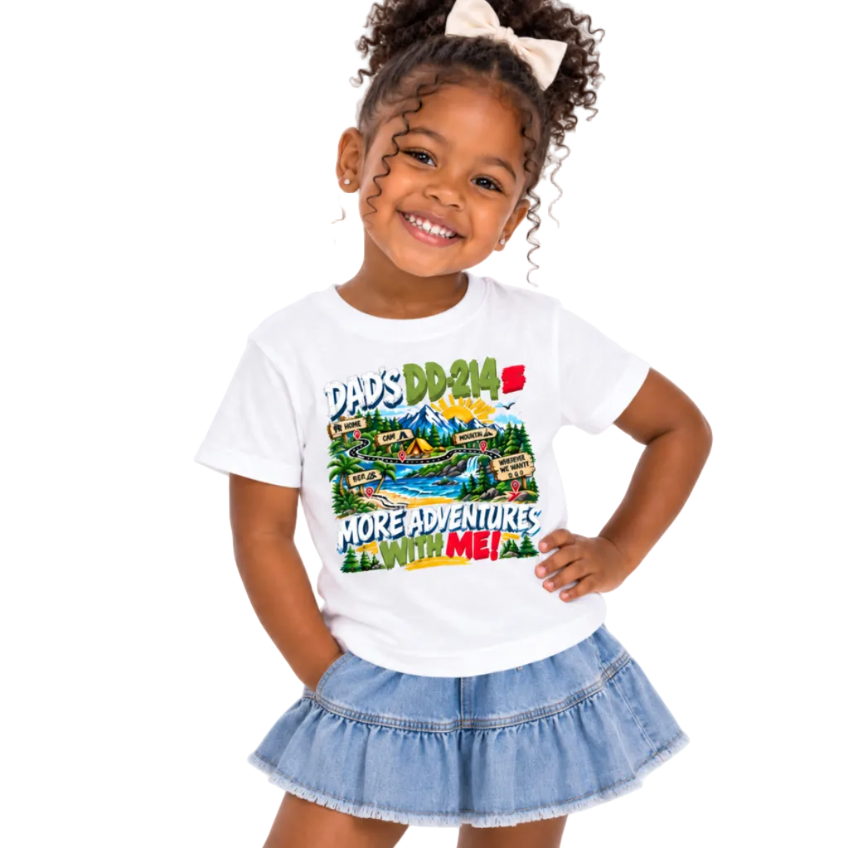 A young girl with curly hair and a white bow smiling while wearing a white graphic t-shirt that reads 'DAD'S DD 214 MORE ADVENTURES WITH ME!' with a colorful landscape illustration, paired with a light blue denim ruffle skirt, against a plain white background.