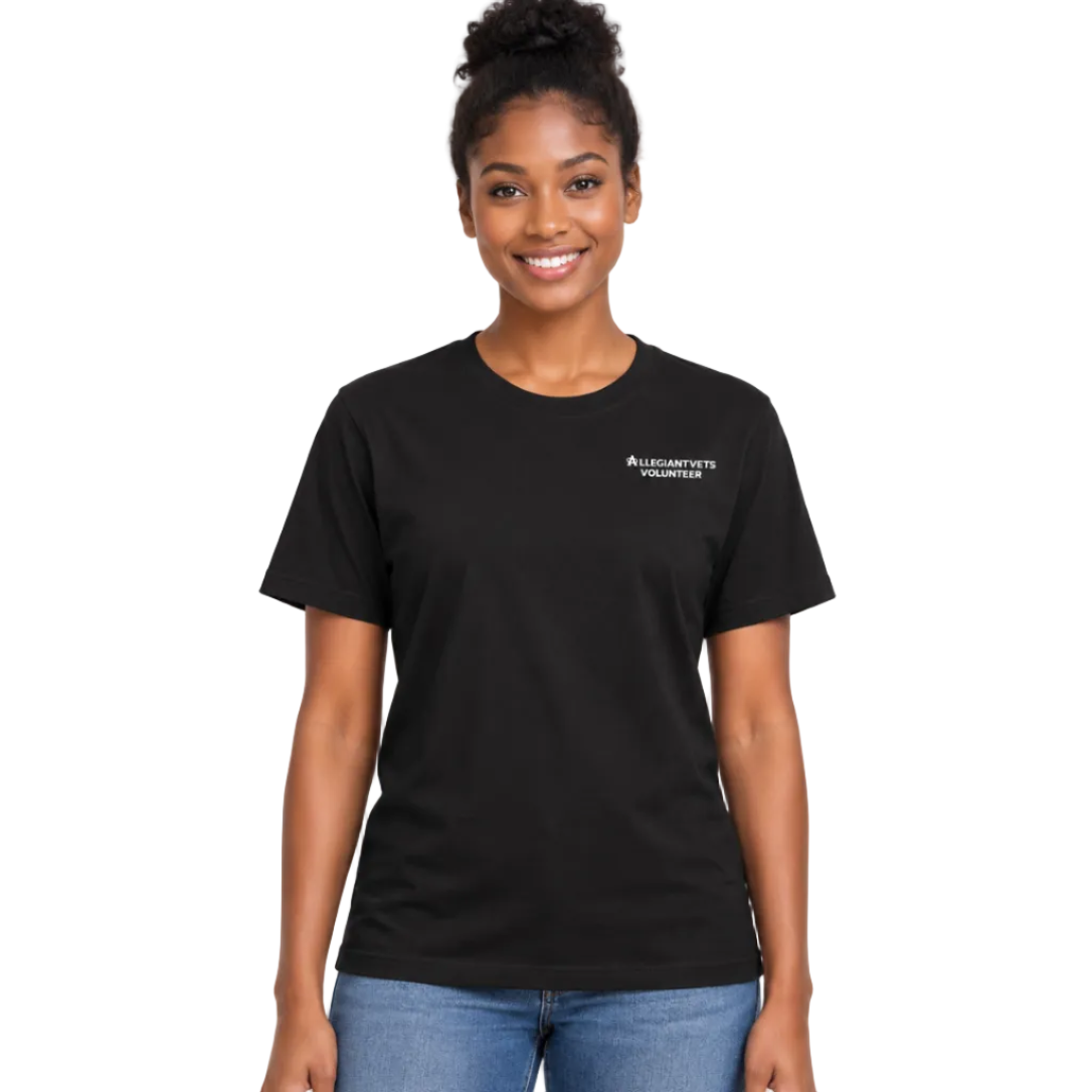 A smiling woman with her hair in a bun wears a black short-sleeve crewneck t-shirt with a small white 'ALLEGIANTVETS VOLUNTEERS' logo on the left chest, paired with blue jeans, against a plain white background.