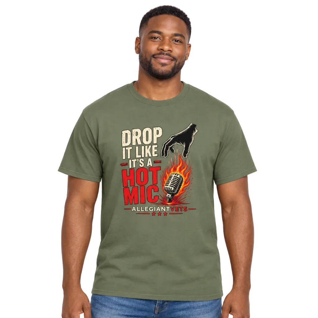 A man wearing an olive green graphic t-shirt with a 'Drop It Like It's a Hot Mic' podcast design, paired with blue jeans, against a plain white background.
