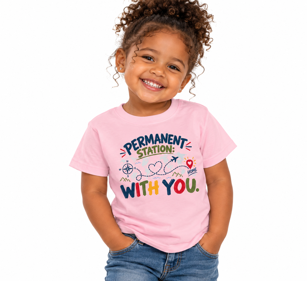 A young child with curly hair smiling and wearing a light pink graphic T-shirt that reads 'PERMANENT STATION: WITH YOU.' in colorful lettering, paired with blue jeans, against a plain white background.