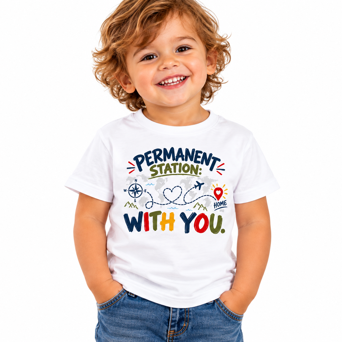 A smiling young boy with curly hair wearing a white graphic t-shirt and blue jeans, standing against a solid white background. The t-shirt features a colorful graphic with the words 'PERMANENT STATION WITH YOU.