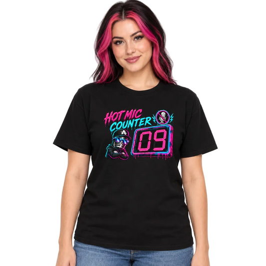 A woman with pink-streaked black hair wearing a black graphic t-shirt with a neon-style 'HOT MIC COUNTER 09' design, paired with blue jeans, against a plain white background.
