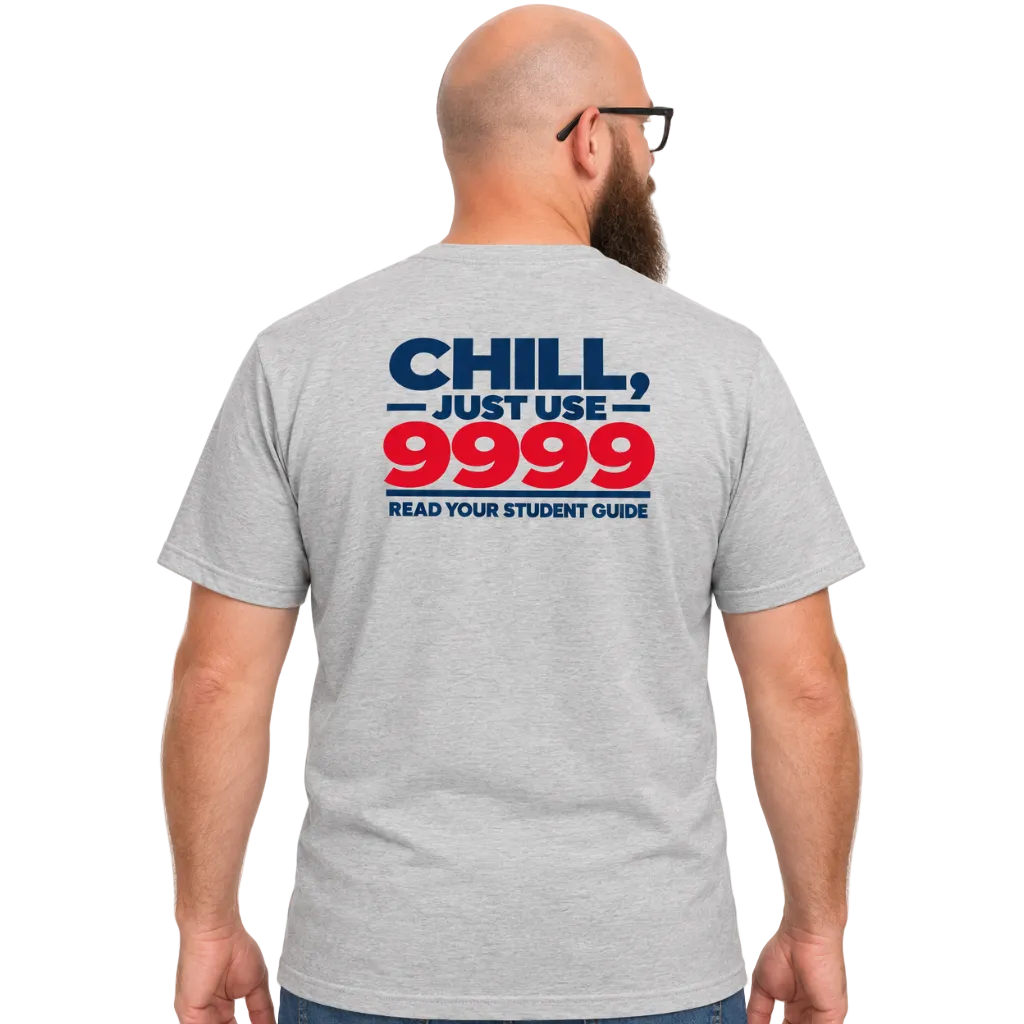 A man viewed from the back wearing a heather gray t-shirt with a bold graphic on the back reading 'CHILL, JUST USE 9999 READ YOUR STUDENT GUIDE' in navy blue and red, paired with blue jeans against a plain white background.